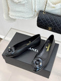 Chanel Camellia Ballet Flats in black lambskin leather with CC camellia embellishment, displayed on Chanel box